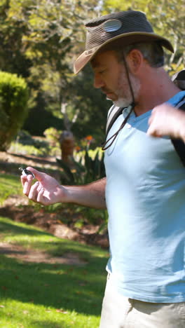 Hiker-with-rucksack-looking-at-compass-at-countryside