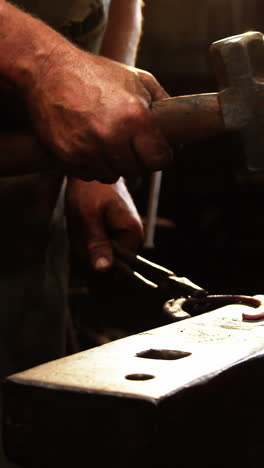 Mid-section-of-blacksmith-working-on-a-horseshoe