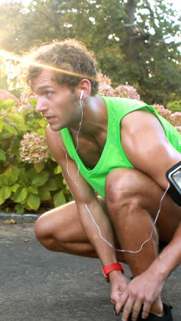 Man-tying-his-shoe-laces-while-jogging-in-park