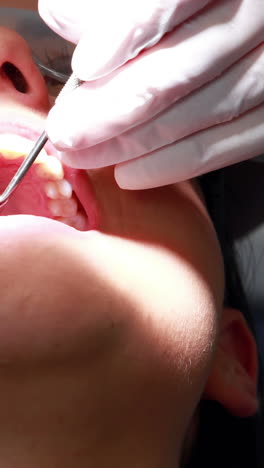 Dentist-examining-a-patients-teeth-in-the-dentists-chair