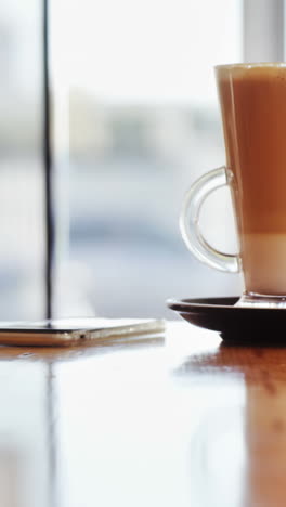 Glas-Kaffee-Und-Mobiltelefon-Auf-Dem-Tisch