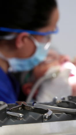 Dentist-examining-a-patients-teeth-in-the-dentists-chair