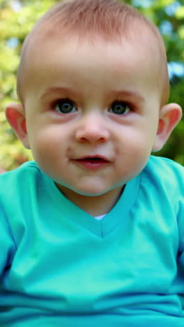 Laughing-baby-boy-sitting-on-the-grass-with-mother-behind-him