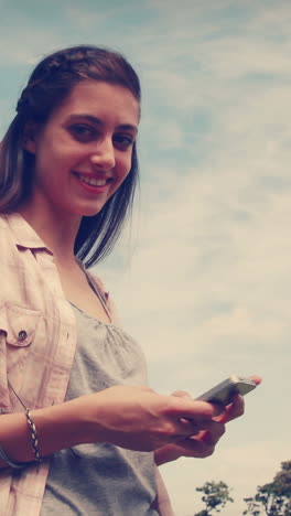 Pretty-brunette-texting-in-the-park