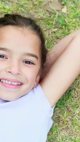 Happy-little-girl-lying-on-grass-and-looking-at-camera