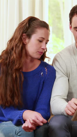 Happy-couple-sitting-on-the-couch-using-the-laptop