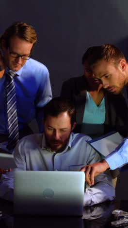 Businessman-discussing-over-laptop-and-document-with-colleague-in-office