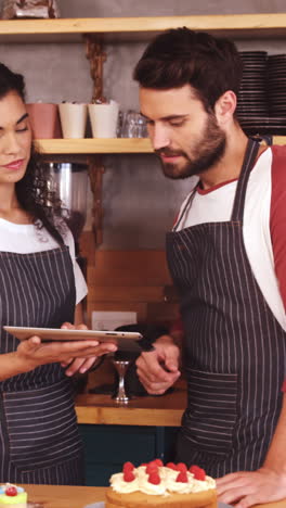 Smiling-waiter-and-waitress-using-digital-tablet-at-counter