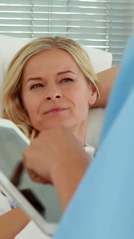 Doctor-using-tablet-computer-in-front-of-patient-bed-