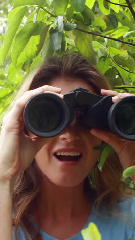 Smiling-woman-with-binoculars-behind-leaves