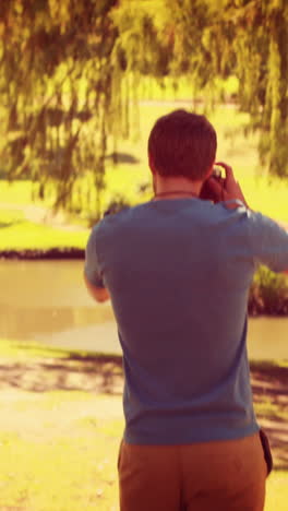 Rear-view-of-man-walking-and-taking-photo-with-retro-camera