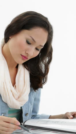 Asian-woman-working-at-desk-writing-in-folder