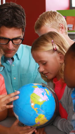 Kids-and-teacher-looking-at-globe-in-library