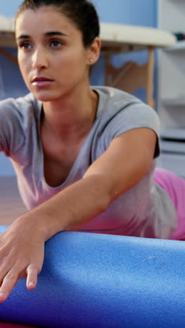 Physiotherapist-assisting-woman-while-exercising-on-exercise-mat