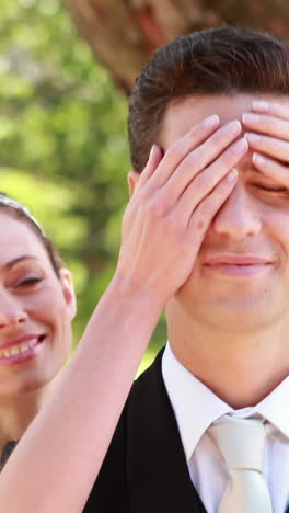 Bride-covering-her-grooms-eyes-and-smiling-at-camera