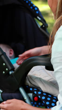 Mother-checking-on-her-sleeping-baby-in-a-pram-in-the-park