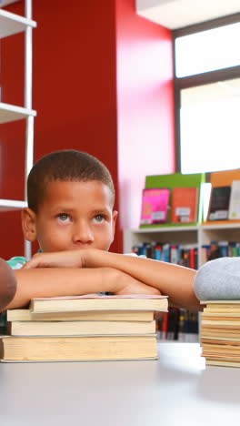 Niños-De-Escuela-Apoyados-En-Una-Pila-De-Libros-En-La-Biblioteca