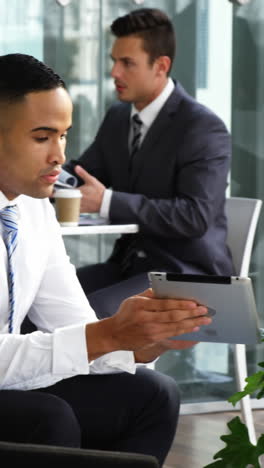 Businessman-discussing-over-digital-tablet-with-colleague-