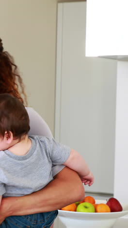 Mother-holding-her-happy-baby-boy-and-talking-on-phone