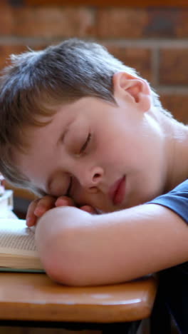 Little-boy-sleeping-on-a-book-in-classroom