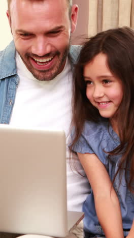 Happy-father-and-daughter-using-laptop