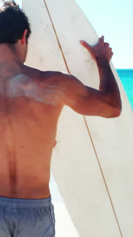 Man-standing-on-beach-with-surfboard