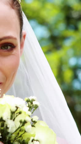 Pretty-bride-smiling-at-camera-and-smelling-her-bouquet