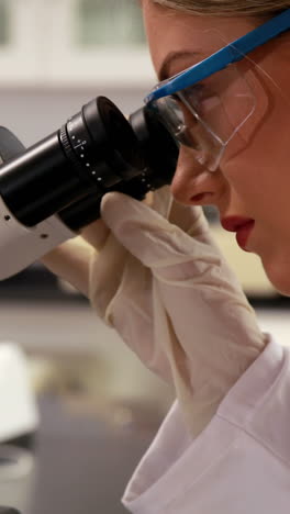 Young-scientist-looking-through-microscope-in-the-lab