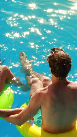 Couple-sitting-on-inflatable-rings-in-the-swimming-pool