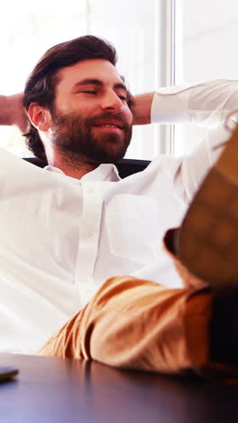 Male-executive-sitting-with-legs-on-table