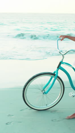 Mujer-Feliz-Caminando-Por-La-Playa-Con-Una-Bicicleta