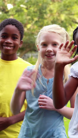 Row-of-cute-pupils-waving-and-smiling-at-camera