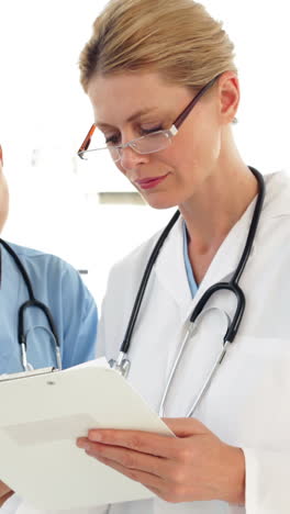 Two-medical-workers-looking-over-a-file-and-looking-at-camera