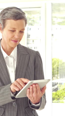 Confident-businesswoman-using-tablet-and-looking-at-camera