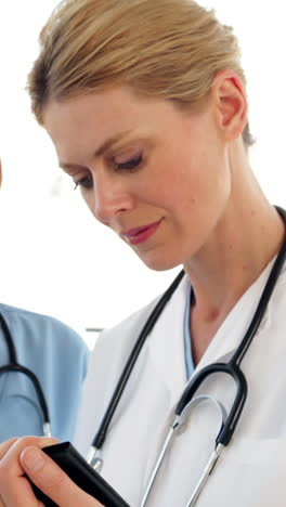 Two-doctors-looking-over-a-file-and-looking-at-camera