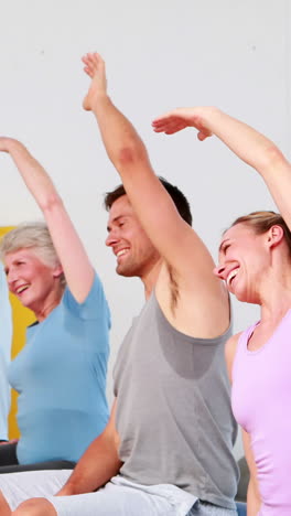 Fitness-group-sitting-on-exercise-balls-stretching-arms