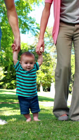 Parents-teaching-their-baby-son-to-walk-on-the-grass