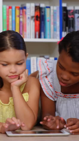 School-kids-and-teacher-using-digital-tablet-in-library