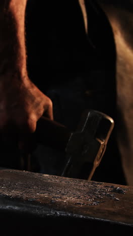 Mid-section-of-blacksmith-walking-with-hammer