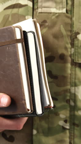 Mid-section-of-soldier-holding-dairy-on-white-background