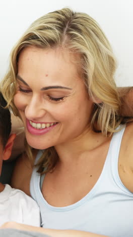 Cute-family-smiling-and-sitting-on-a-bed