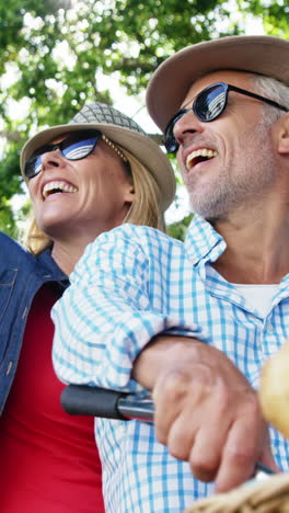 Mature-couple-is-smiling-and-pointing-on-the-same-bike-in-the-street