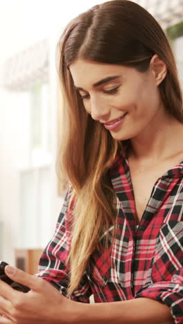 Smiling-woman-using-smartphone-while-drinking-coffee