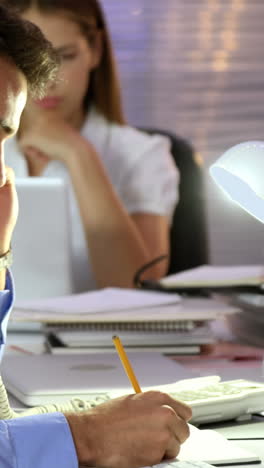 Businessman-talking-on-the-phone-while-writing-in-diary