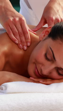 Happy-brunette-enjoying-a-massage-poolside