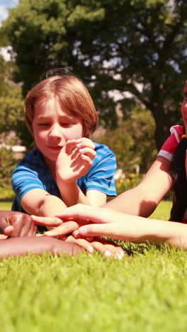 Cute-pupils-lying-on-the-grass-with-hands-together