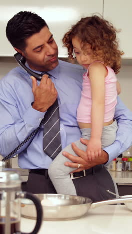 Smiling-father-holding-his-young-daughter-talking-on-the-phone