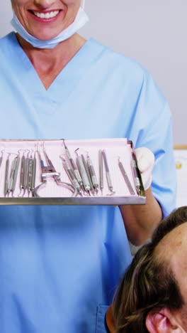 Smiling-dental-assistant-holding-tray-with-equipment-in-dental-clinic