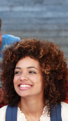 Happy-students-sitting-on-steps-smiling-at-camera