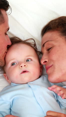 Baby-boy-in-blue-babygro-with-happy-parents-on-bed